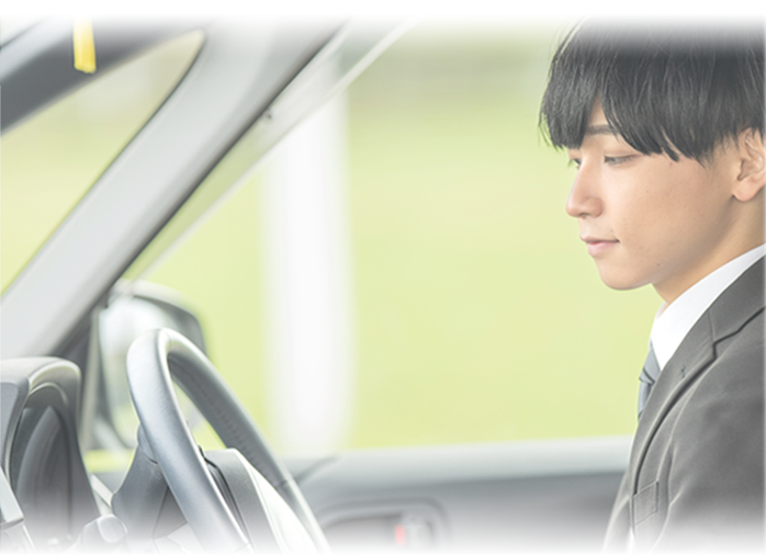 車の運転席に座りハンドルを見る男性の写真